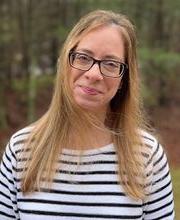 headshot photo of Holly Ferreira with long straight dirty blonde hair, wearing 黑色的 rimmed glasses and a white and 黑色的 striped jersey