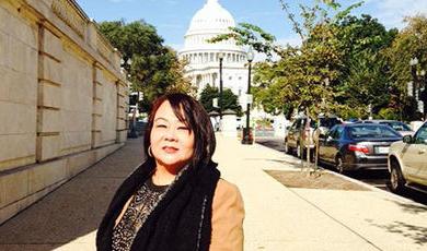 My Lan Tran stands o a sidewalk in front of the U.S. 国会大厦.