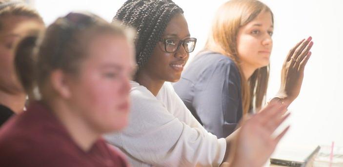 students raising their hands in class