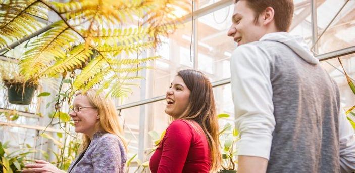 Professor 和 students in greenhouse surrounded by plants