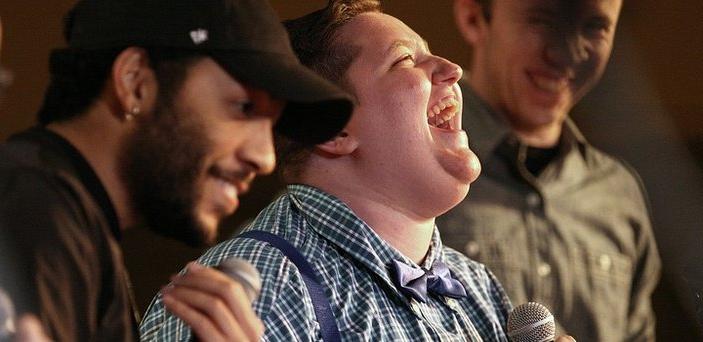 Three students with microphones smiling and laughing